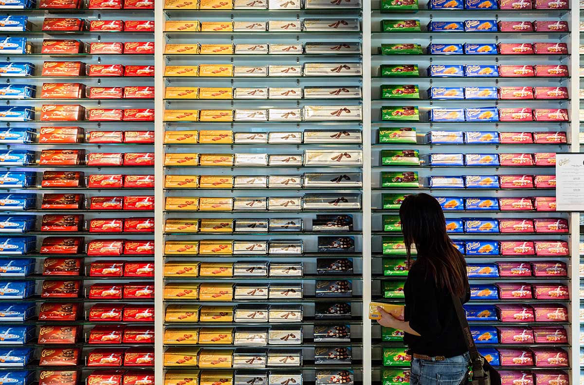 Woman Choosing Chocolate Bar in Modern Supermarket Aisle